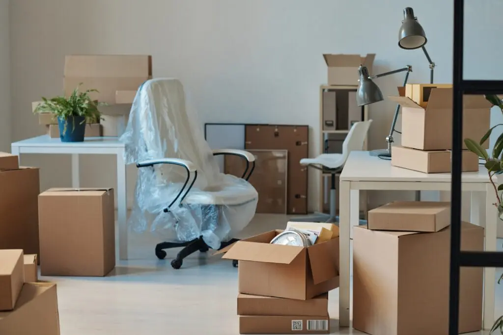 Office chair covered with plastic among packed boxes ready for moving.