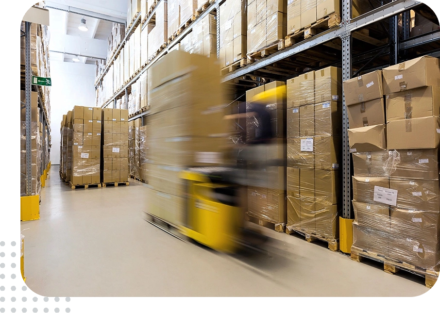 Motion-blurred forklift passing stacked cardboard pallets
